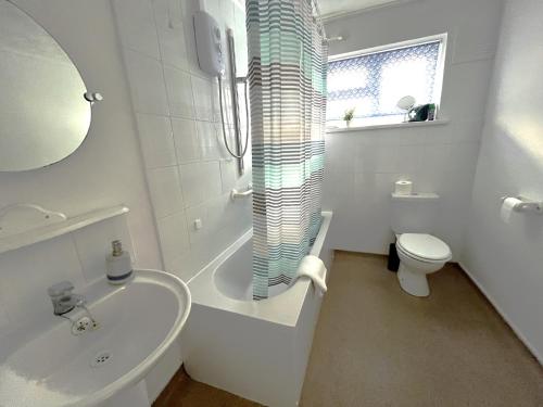 Baño blanco con aseo y lavamanos en Harrowby Home, en Lincolnshire