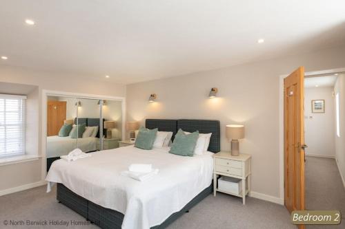 um quarto com uma grande cama branca e um espelho em Number 55 Apartment em North Berwick