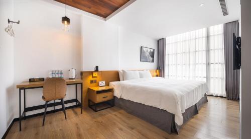 a bedroom with a bed and a desk with a chair at BlueSky Hotel in Taichung