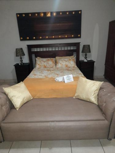 a large bed in a bedroom with a large headboard at Charis Guesthouse in Hartswater