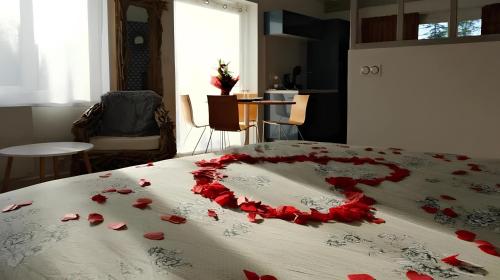 uma cama com pétalas de rosa vermelhas em Le Cocon des Layes em Les Essarts-le-Roi
