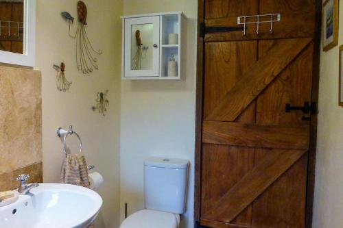 a bathroom with a wooden door and a toilet and a sink at East Titchberry Cottage - Thatched cottage charm in rural North Devon in Hartland