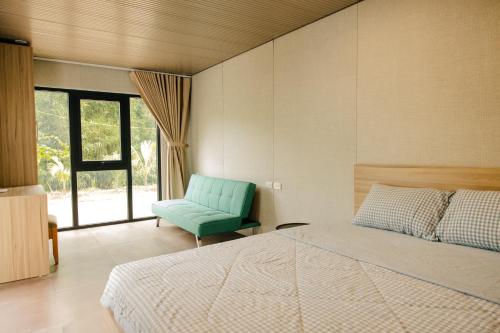a bedroom with a bed and a green chair at Halo Retreat in Hòa Bình