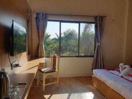 1 dormitorio con ventana, 1 cama y 1 silla en Hotel Ananda Inn en Lumbini