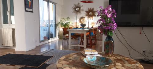 un salon avec une table et un vase avec des fleurs violettes dans l'établissement maison Rulman, à Nîmes