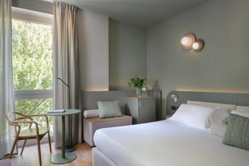 a bedroom with a bed and a chair and a window at Hotel Ilaria in Lucca