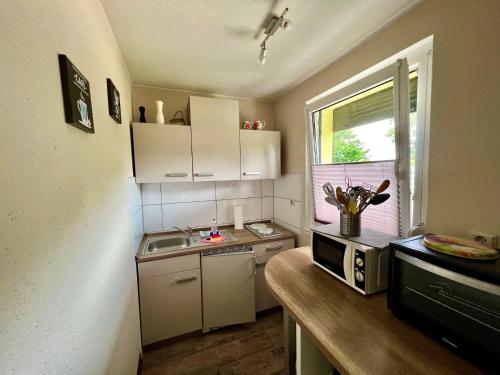 eine kleine Küche mit einer Spüle und einer Mikrowelle in der Unterkunft Ferienbungalow Muranko am Kiessee in Krugsdorf