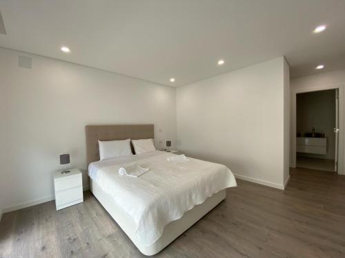 a white bedroom with a large bed and a white wall at Luxury villa surrounded by nature and beach in Amora