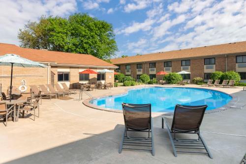 a swimming pool with chairs and tables and a building at Best Western Plus Ramkota Hotel in Sioux Falls