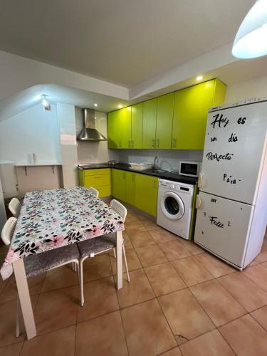 een keuken met groene kasten, een tafel en een koelkast bij Apartamento Arrabal in Teruel