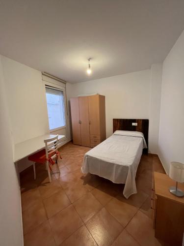 Schlafzimmer mit einem Bett, einem Schreibtisch und einem Fenster in der Unterkunft Apartamento Arrabal in Teruel