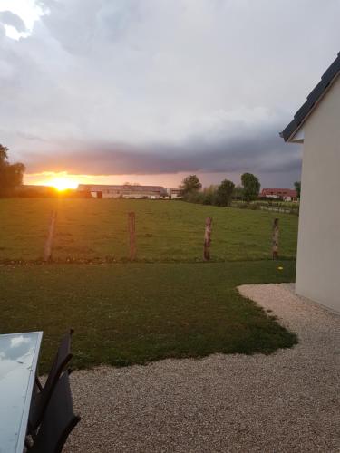einen Sonnenuntergang über einem Feld mit einem Zaun in der Unterkunft studio au cœur de la vannerie in Fayl-Billot