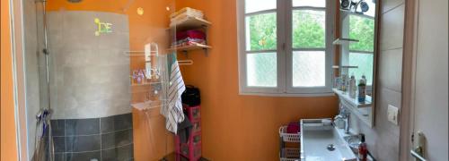 cocina con paredes de color naranja, lavabo y ventana en L’Albizia, en La Tranche-sur-Mer