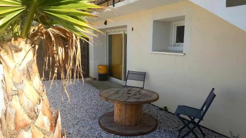 un patio con una mesa de madera y una palmera en L'Atelier d'Emilie, en Bessines