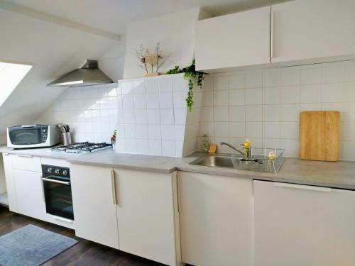 a kitchen with white cabinets and a sink at Révélation Liège in Liège
