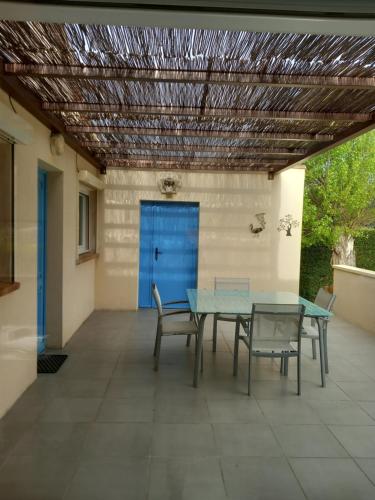 un patio con mesa y sillas y una puerta azul en Gîte Le vallon des vignes, en Vallon-Pont-dʼArc