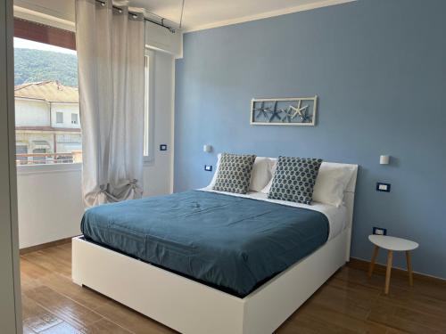 una camera da letto con un letto con pareti blu e una finestra di Elite19 Apartment Plus 39 ad Ameglia