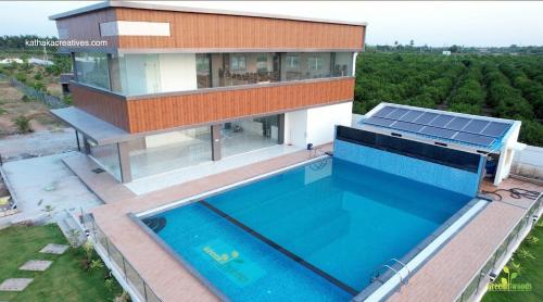 a house with a swimming pool in front of a house at Green Woods Resort in Anantapur