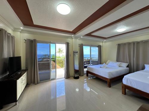 a bedroom with two beds and a television and a balcony at Pearl Resort Panglao,Dauis Bikini Beach in Dauis
