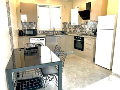 a kitchen with a white refrigerator and a table with chairs at Cosy S3 Apartment in Sidi Bou Said Village in Sidi Bou Saïd