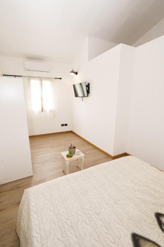 a white bedroom with a large bed and a table at Il Fortino di San Francesco in Collestrada
