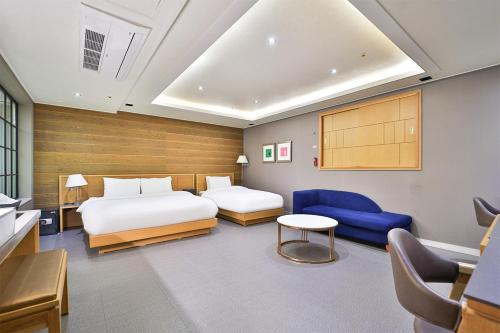 a bedroom with two beds and a blue couch at Seomyeon IB Hotel in Busan