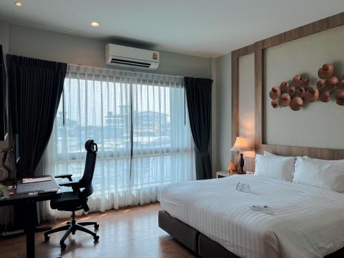 a hotel room with a bed and a desk and a window at Civilize Hotel in Udon Thani