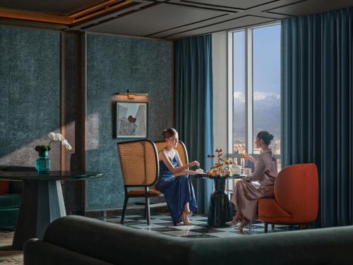 two women sitting at a table in a hotel room at Conrad Urumqi in Ürümqi