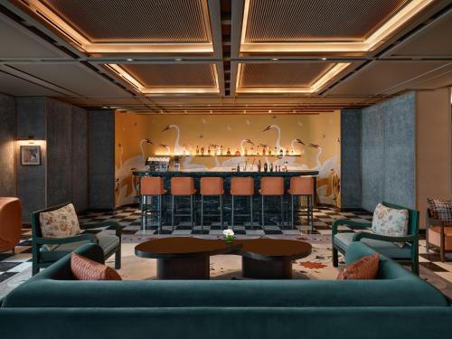 a bar in a hotel lobby with chairs and a table at Conrad Urumqi in Ürümqi