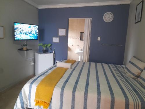 um quarto com uma cama e uma televisão na parede em The Rose Guesthouse em Witbank