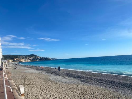 un groupe de personnes marchant sur la plage dans l'établissement Heart of Nice-Rooftop Seaside Studio, à Nice