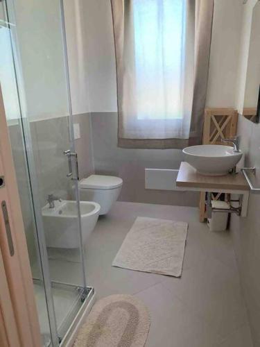 a bathroom with a shower and a sink and a toilet at Villa Cristallina Piscina privata, Wi-Fi & Netflix in Stintino
