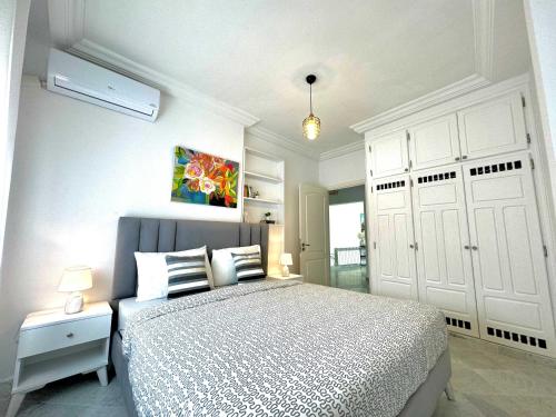 Cosy S3 Apartment in Sidi Bou Said Village في سيدي بو سعيد: غرفة نوم بيضاء مع سرير وخزانة بيضاء