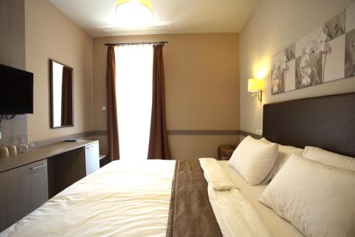 a bedroom with a large white bed with a window at Hotel La Riva in Siófok