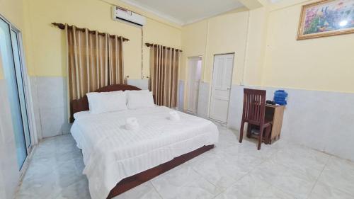 a bedroom with a large white bed and a chair at Koh Rong Homestay in Kaôh Rŭng (3)