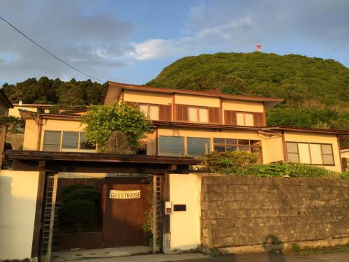 a house with a hill in the background at Hakodateyama Guest House in Hakodate