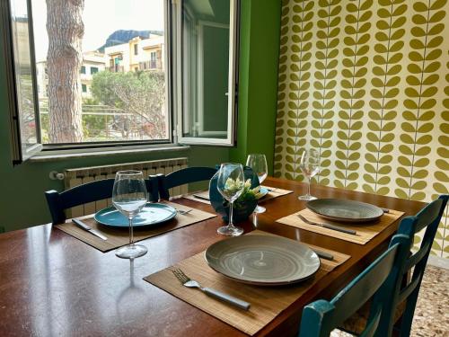 a wooden table with plates and wine glasses on it at Sperlonga Paradise Central Apartment in Sperlonga