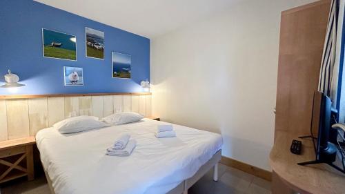 a bedroom with a bed with white sheets and a blue wall at Appartement avec terrasse vue sur le parc de golf in Fort-Mahon-Plage