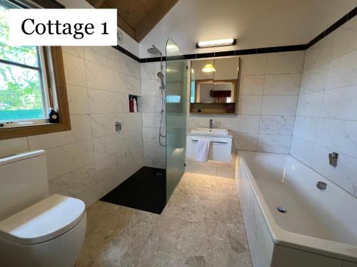 a bathroom with a tub and a toilet and a sink at Olinda Country Cottages in Olinda