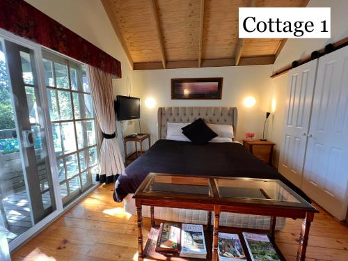 Schlafzimmer mit einem Bett und einem Tisch mit einem Couchtisch in der Unterkunft Olinda Country Cottages in Olinda