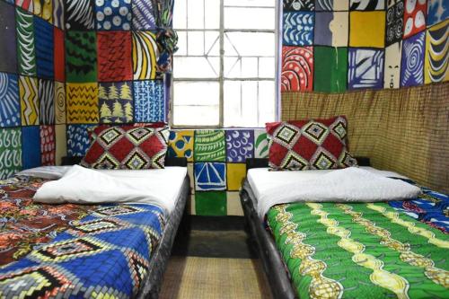 NyakinamaにあるRoom in BB - Red Rocks Rwanda - Triple Roomのベッド2台が備わるカラフルな壁の客室です。
