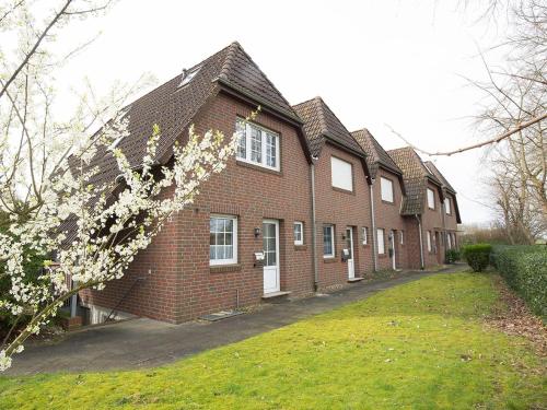 une maison en briques avec un arbre en fleurs devant dans l'établissement Ferienhaus Heineke, FeWo Vermittlung Nordsee, à Dangast