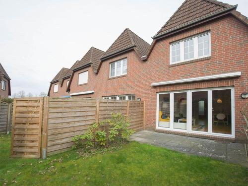 une maison avec une clôture en bois dans la cour dans l'établissement Ferienhaus Heineke, FeWo Vermittlung Nordsee, à Dangast