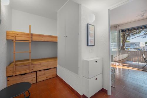 Cette chambre est dotée d'un mur blanc et d'une étagère en bois. dans l'établissement AS23988-Studio cabine, dans une Résidence directe sur Plage, au Grau-du-Roi