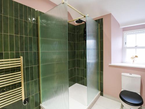 a bathroom with a shower with green tiles at The Loft at The Old Dog Thorpe in Ashbourne