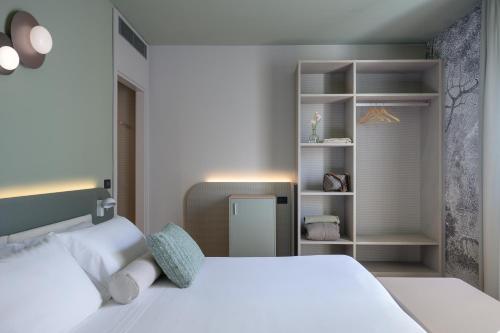 a bedroom with a white bed and a book shelf at Hotel Ilaria in Lucca