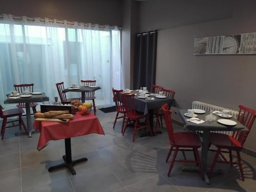 een eetkamer met zwarte tafels en rode stoelen bij Hôtel Les Thermes in Jonzac