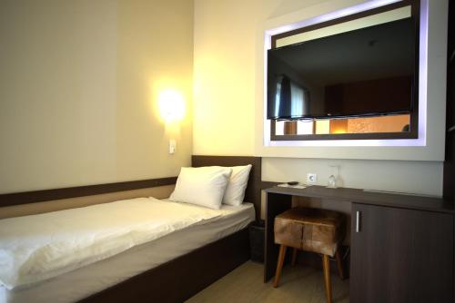 a small room with a bed and a television at Hotel La Riva in Siófok