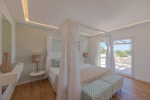 um quarto com uma cama de dossel e uma varanda em Casa da Praia em Galé