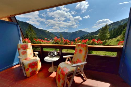 a balcony with two chairs and a view of mountains at Hotel St. Oswald in Bad Kleinkirchheim